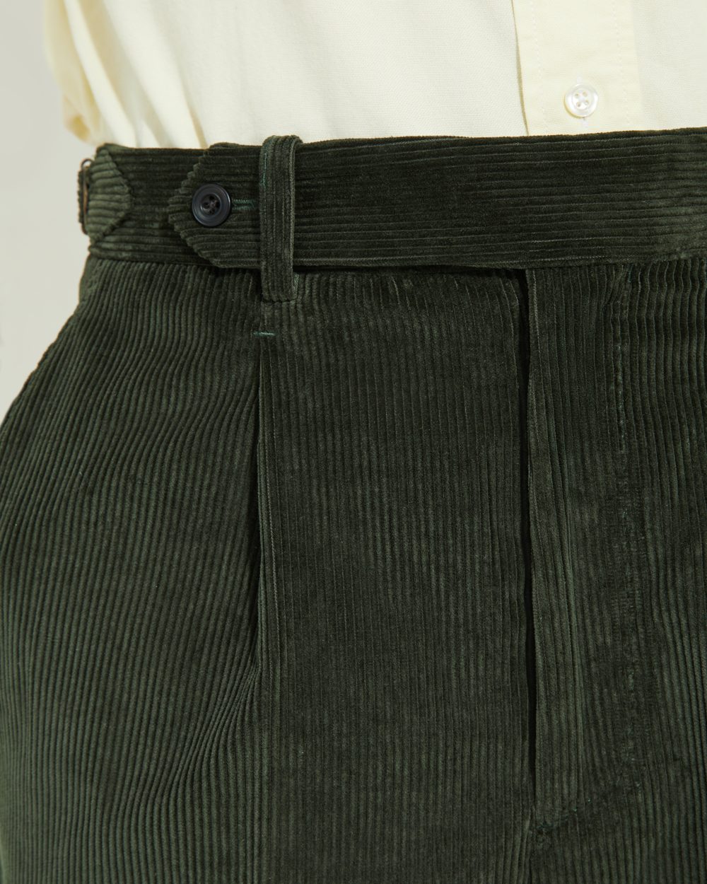 Détail des ajusteurs latéraux, pince et patte prolongée du pantalon en velours vert Scavini.