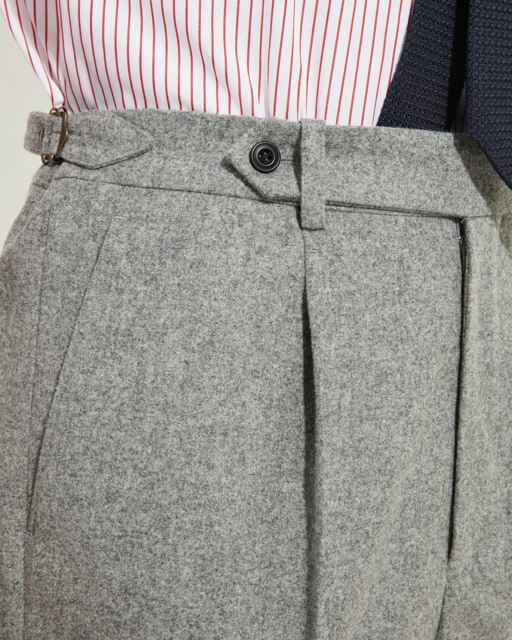 Détail des ajusteurs latéraux, de la pince avant et de la patte prolongée du pantalon flanelle grise Scavini.