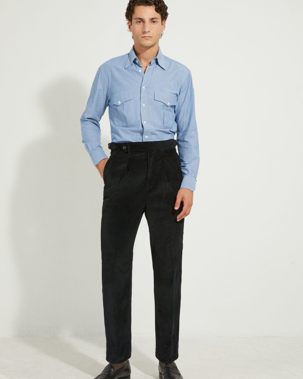 Pantalon en velours côtelé noir Scavini porté avec une chemise en chambray.